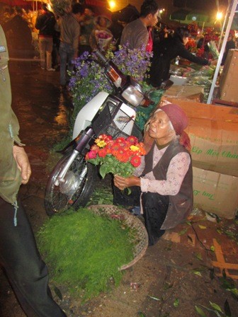 Bên cạnh những hàng hoa lộng lẫy, tấp nập, bó hoa của bà cụ trông thật nhỏ nhoi như chính bà: “Mua hoa đi cô, tự tay tôi cắt vườn nhà đấy, tươi lắm!”.