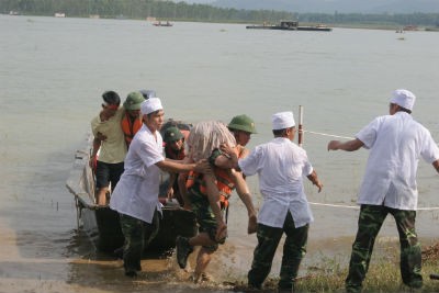 Tiếp cận những người bị nước cuốn trôi đưa lên xuồng để về trạm cấp cứu