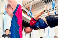 Một hành khách nam đã leo lên tay nắm và thanh sắt trên tàu để thực hiện động tác hít xà đơn