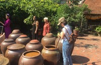 Du khách trải nghiệm hoạt động làm tương ở Làng cổ Đường Lâm. (Ảnh: PV)