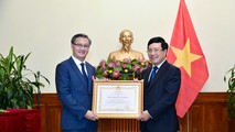 Phó Thủ tướng, Bộ trưởng Ngoại giao Phạm Bình Minh trao Huân chương Lao động hạng Nhất của Chủ tịch nước Việt Nam cho Đại sứ Lào tại Việt Nam Thongsavanh Phomvihane. Ảnh: BNG