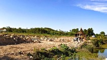 Xe máy đào đang múc đất lên xe tải chở đi ra ngoài để san lấp nơi khác.