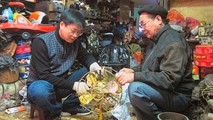 Ông Phúc (phải) và anh Đức đang phục chế một cây quạt cổ. Ảnh tư liệu.