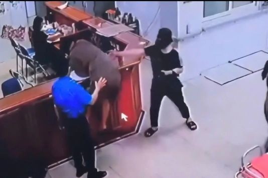 Hình ảnh người đàn ông chồm qua quầy làm thủ tục để hành hung nhân viên y tế. Ảnh: cắt từ clip