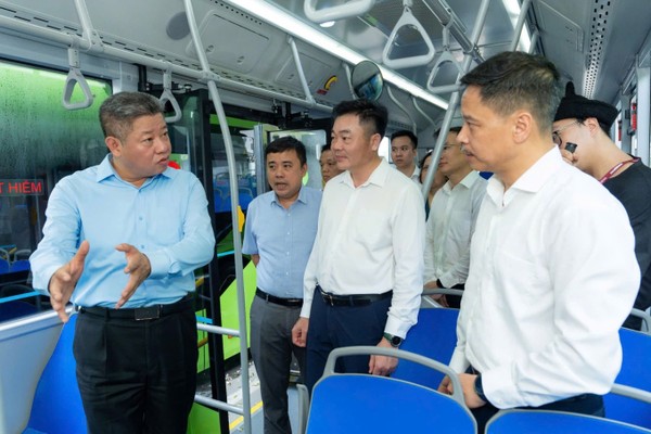 Ông Nguyễn Mạnh Quyền (ngoài cùng bên trái) trao đổi với các đại biểu dự khai trương tuyến buýt điện số 43. (Ảnh: Tuấn Cao)