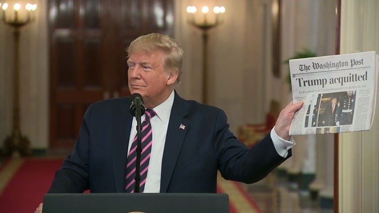 Trump cầm tờ Washington Post có bản tin ông được Thượng viện tha bổng. Ảnh: CNN.