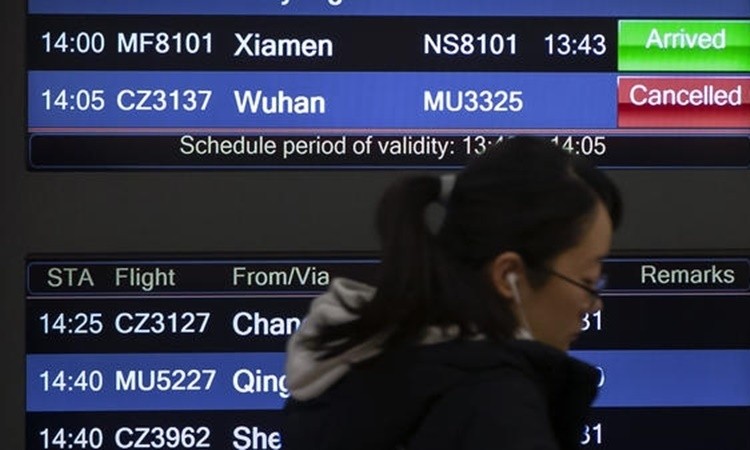 Một hành khách đi qua tấm bảng thông báo tình trạng chuyến bay tại sân bay Bắc Kinh ngày 23/1. Ảnh: AP.