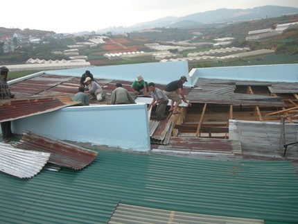 Nhà ông Lành bị tốc mái do lốc xoáy đang được bà con lối xóm hỗ trợ lợp lại