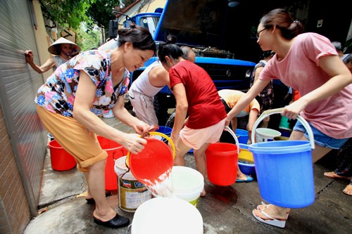 Người dân chia nhau từng xô nước từ xe bồn. Ảnh: MH