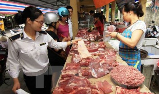 Nhân viên thú y kiểm tra hộ kinh doanh thịt lợn tại chợ. Ảnh: TTXVN