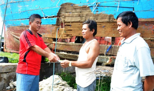 Thuyền trưởng Nguyễn Văn Cư (bên trái) cùng cán bộ Nghiệp đoàn đến trao tiền hỗ trợ cho chủ tàu cá bị nạn