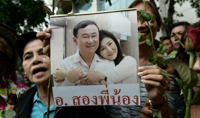 Người dân Thái Lan cầm ảnh bà Yingluck và anh trai