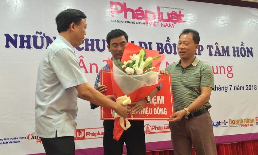 Tiến sĩ Đào Văn Hội, Tổng Biên tập Báo PLVN (bên phải), cùng lãnh đạo địa phương trao quà cho một bạn đọc khó khăn tại miền Trung tháng 7/2018
