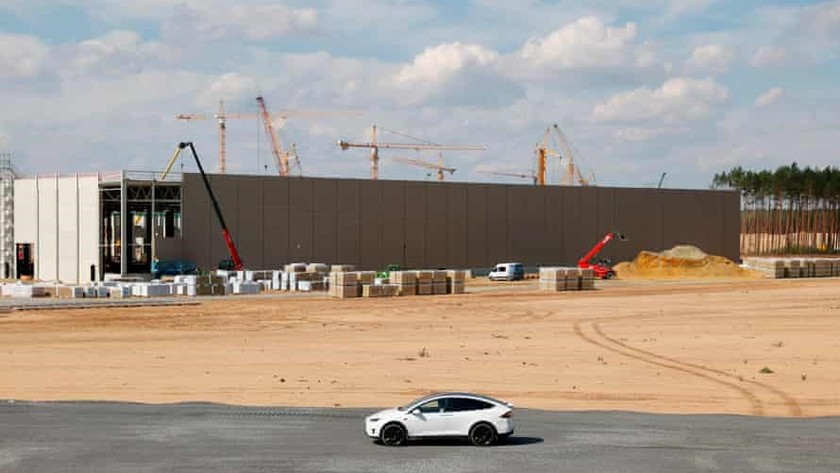 Elon Musk thị sát công trình xây dựng siêu nhà máy trên một chiếc xe điện Tesla © The Guardian.