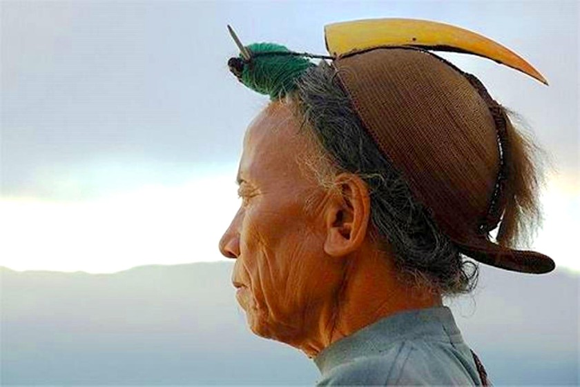 A tribal man in Asia with a headdress decorated with a hornbill beak.