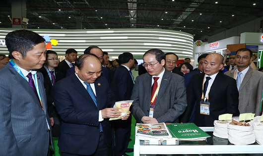Thủ tướng Chính phủ Nguyễn Xuân Phúc lắng nghe Lãnh đạo Hapro giới thiệu về sản phẩm Gạo Hapro Đồng Tháp tại Hội chợ nhập khẩu Quốc tế Trung Quốc 2018 (11/2018)