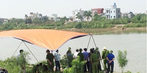 Lực lượng chức năng đang khám nghiệm tử thi sau khi vớt được thi thể nạn nhân - Ảnh: CAND