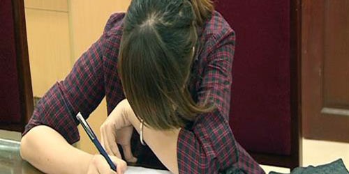 Nữ sinh viên đọc bài thi từ quán cà phê vào phòng thi. Ảnh: Xuân Hoa.