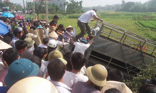 Lực lượng chức năng và người dân đang cố gắng đưa nạn nhân ra khỏi xe tải.