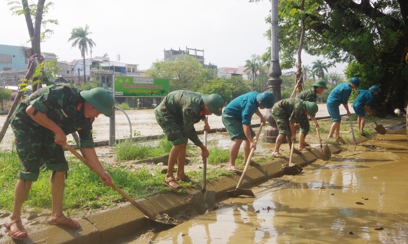 Cán bộ, chiến sĩ Bộ CHQS tỉnh Thừa Thiên Huế nỗ lực dọn bùn khơi thông dòng chảy, bảo đảm người dân lưu thông an toàn. Ảnh: Quỳnh Nga