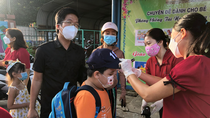 Giáo viên đón học sinh tại cổng trường, đo thân nhiệt và hướng dẫn các em thực hiện rửa tay sát khuẩn. 