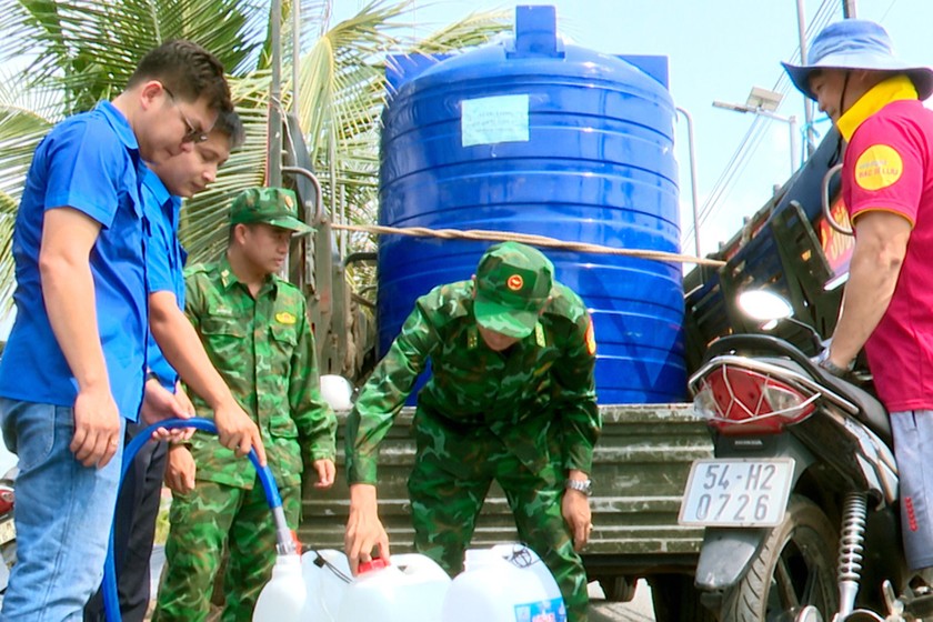 Cán bộ, chiến sỹ, đoàn viên bơm nước vào can chứa cho người dân. Ảnh: Luận Quân