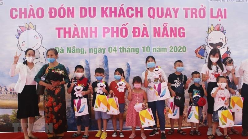 Tặng quà cho đoàn du khách đầu tiên trở lại du lịch thành phố sau dịch Covid-19. Ảnh TTXVN