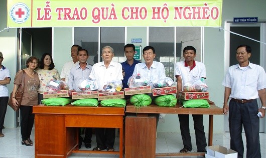 Ông Út Gìn (giữa) trao quà Tết cho hộ nghèo xã Tân Bình.