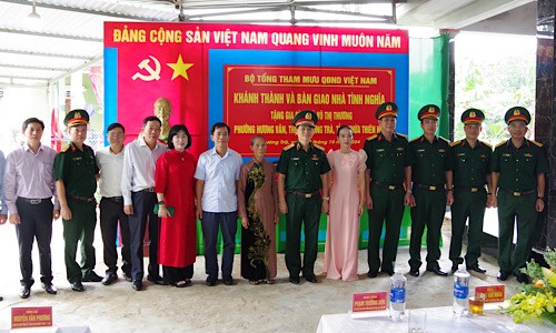 Đại diện Bộ Tổng tham mưu Quân đội nhân dân Việt Nam, lãnh đạo tỉnh, thị xã Hương Trà chụp ảnh lưu niện với gia đình bà Võ Thị Thương tại lễ bàn giao.