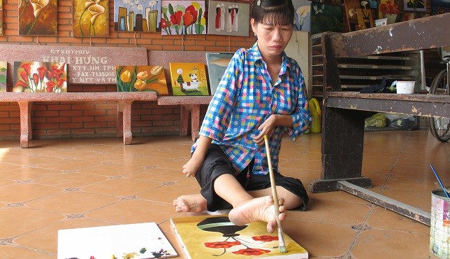 Chị Sậm đang vẽ tranh bằng chân.