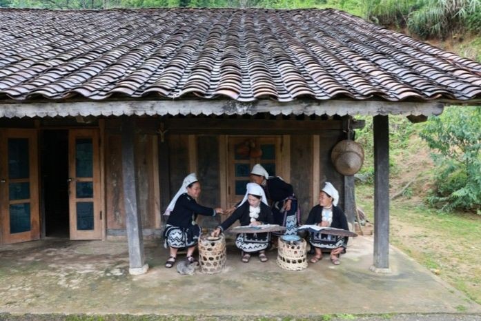 Bà con làng Hoài Khao trình diễn nghề in thêu hoa văn bằng sáp ong dưới mái nhà âm dương. (Ảnh: Ngọc Anh)