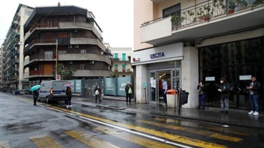 Người mua sắm xếp hàng trong mưa ở Sicily, Ý. Ảnh: Reuters 