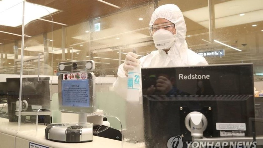 Một nhân viên nhập cư khử trùng bàn làm việc của cô tại sân bay quốc tế Incheon, Seoul, ngày 8/4/2020. (Yonhap)