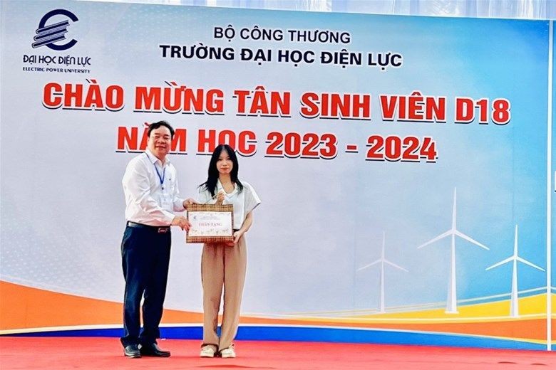 PGS.TS Vũ Đình Ngọ - Bí thư Đảng ủy, Chủ tịch Hội đồng Trường trao quà cho tân sinh viên khóa D18 đầu tiên đến nhập học.