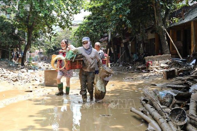 Người dân lội bùn khi di chuyển trên 2 tuyến phố Thanh Niên và Trần Hưng Đạo (TP Yên Bái, tỉnh Yên Bái), chiều 14/9. Ảnh: TTXVN