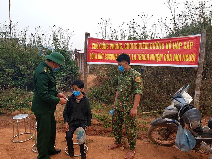 Cán bộ Đồn Biên phòng tại chốt kiểm dịch, thực hiện kiểm tra sức khỏe, đo nhiệt độ cơ thể cho người dân. 