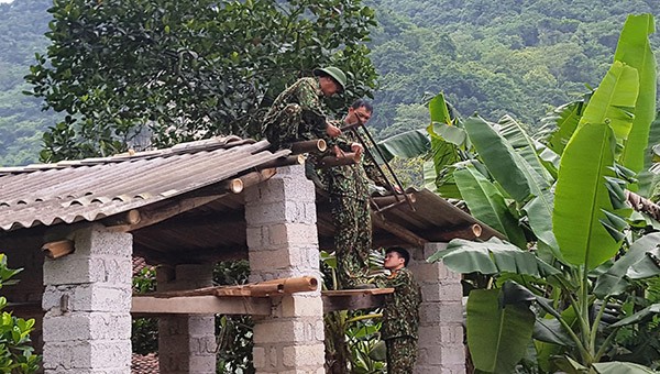 Chiến sĩ Đồn Biên phòng Cửa khẩu Quốc tế Tà Lùng giúp người dân xã Bế Văn Đàn, huyện Quảng Hòa, tỉnh Cao Bằng di dời chuồng gia súc ra khỏi gầm sàn nhà ở.