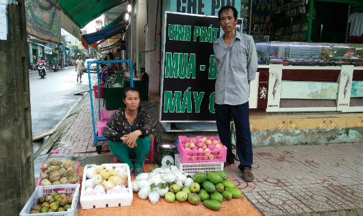 Ông Dũng bên sạp hàng trái cây của người vợ