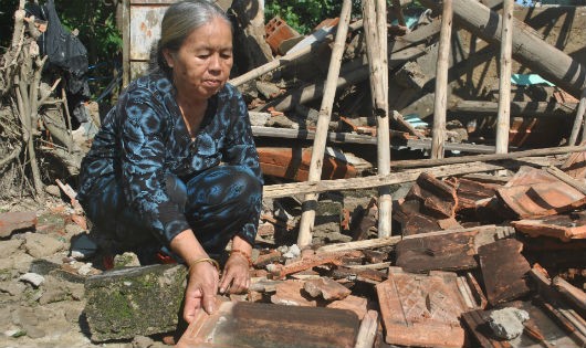 Cụ Chín đang tìm kiếm những viên ngói còn nguyên trong căn nhà đổ nát.