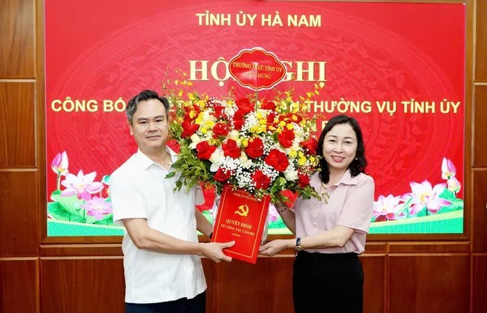 Phó Bí thư Thường trực Tỉnh ủy Hà Nam Đinh Thị Lụa trao quyết định và tặng hoa chúc mừng ông Trần Nguyễn Hiền Anh