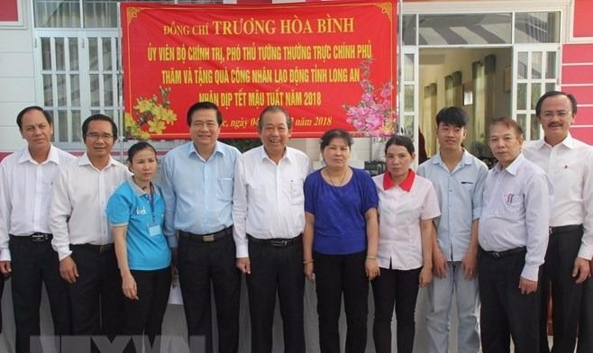 Phó Thủ tướng Trương Hòa Bình thăm và tặng quà Tết cho công nhân ở Long An. (Ảnh: Bùi Giang/TTXVN)