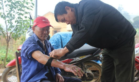 Ông Lê đang hành nghề chữa bệnh cho một người dân trong bản bị rắn cắn