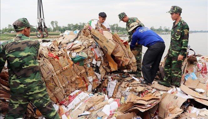 Cán bộ, chiến sĩ Đồn Biên phòng Cửa khẩu Long Bình bốc dỡ, thống kê số tang vật thu được ngày 22/3. Ảnh TTXVN