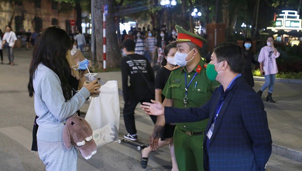 Lực lượng chức năng nhắc nhở một người dân không đeo khẩu trang tại phố đi bộ Hồ Gươm. Ảnh: VnExpress.