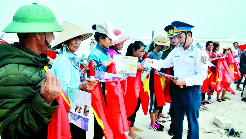 CSB và BĐBP tặng cờ Tổ quốc và phát tờ rơi tuyên truyền pháp luật cho ngư dân trước khi đi biển.