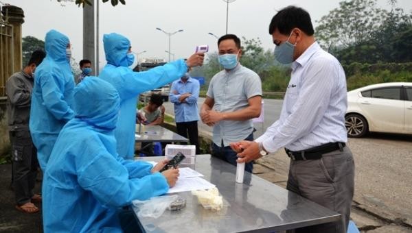 Lực lượng chức năng tại chốt kiểm soát đo thân nhiệt và hướng dẫn người dân rửa tay sát khuẩn.