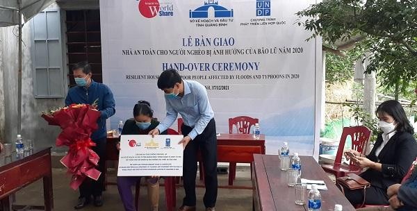 Ông Hoàng Đức Thiện, Phó Giám đốc Sở Kế hoạch & Đầu tư Quảng Bình trao biển tượng trưng nhà an toàn chống chịu bão, lụt cho gia đình bà Lê Thị Học, thôn Hoàng Đàm, xã Sơn Thủy, huyện Lệ Thủy.