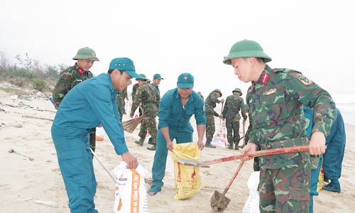 Cán bộ, chiến sĩ bộ đội thường trực và dân quân địa phương thu gom dầu thô và rác thải tại bãi biển.