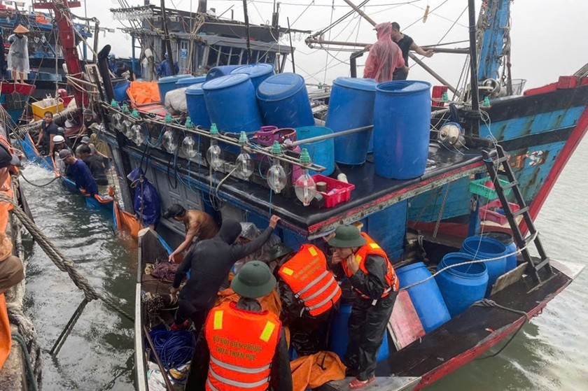 Cán bộ, chiến sĩ Đồn Biên phòng cửa khẩu cảng Thuận An cùng ngư dân địa phương trục vớt tàu cá.