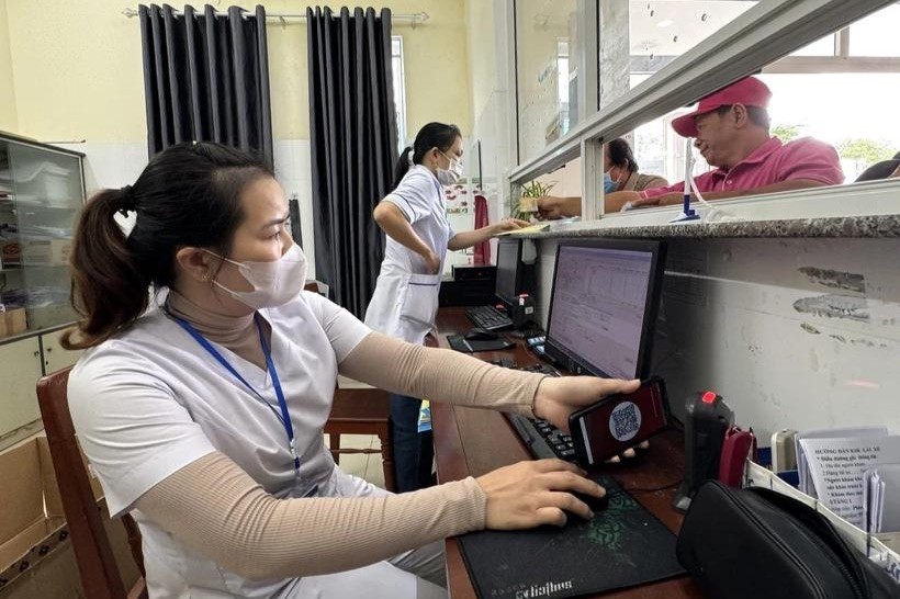 Nhân viên y tế quét mã lấy số và đăng ký khám bệnh tại các ki-ốt phát số tự động. (Ảnh: Đinh Hương/TTXVN) 